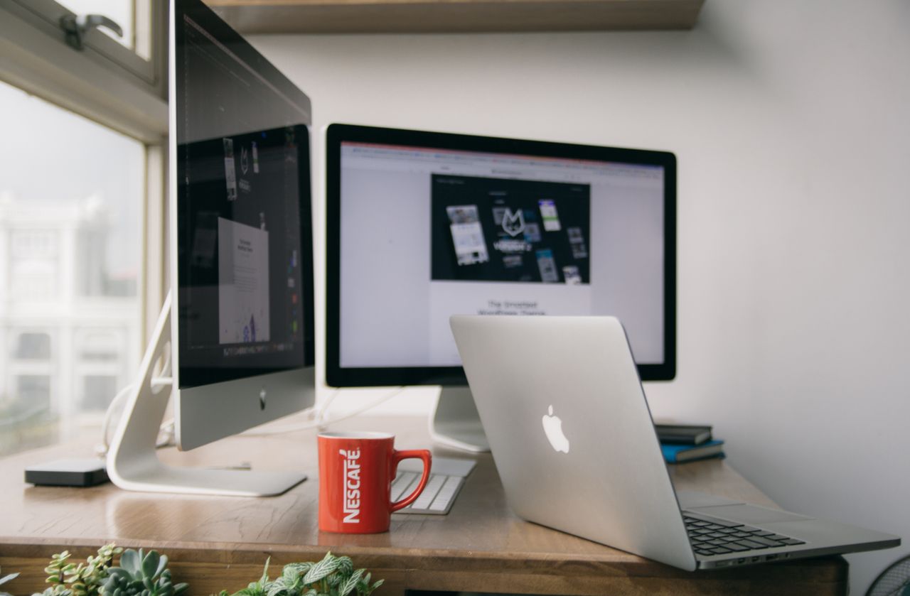 our-story A bright modern office setup with computers and a mug on a desk.